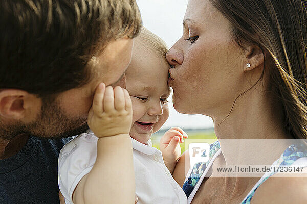 Nahaufnahme von Mitte Erwachsenen Eltern küssen Baby Tochter