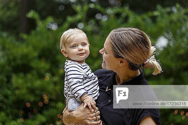 Mother holding baby girl  outdoors  smiling