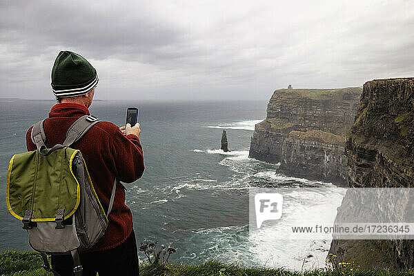 Mid adult man taking photo  Cliffs of Moher  The Burren  County Clare  Ireland