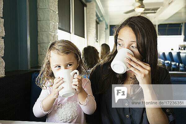 Mutter und Kleinkind trinken Tassen Kaffee im Diner