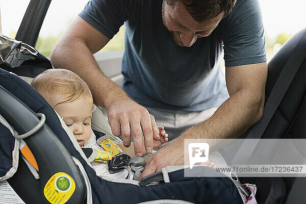 Mid erwachsenen Mann Befestigung Sicherheitsgurt auf Baby Töchter Autositz