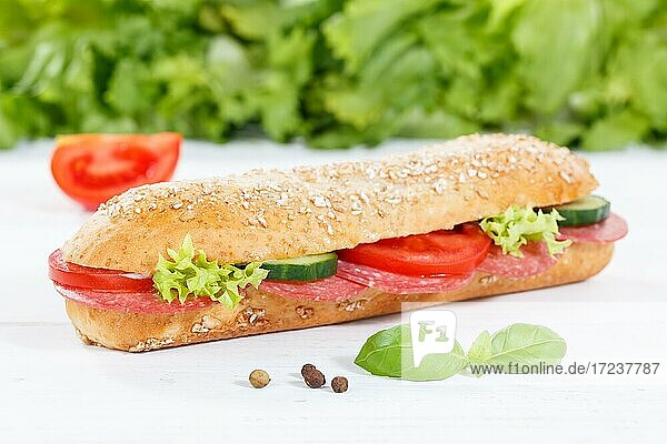 Sandwich Baguette Vollkorn Brötchen belegt mit Salami Schinken auf Holzbrett