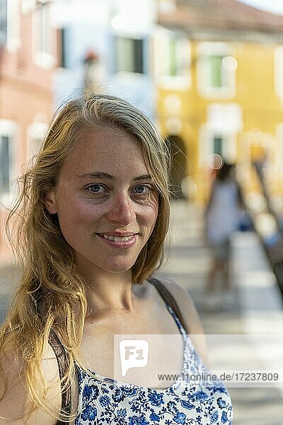 Portrait einer Jungen Frau vor einer roten Wand  blickt in die Kamera  Insel Burano  Venedig  Venetien  Italien  Europa
