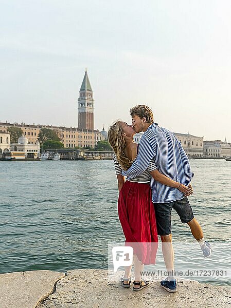 Junges verliebtes Paar steht am Meer und genießt Blick auf Markusplatz mit Campanile di San Marco  Venedig  Venetien  Italien  Europa