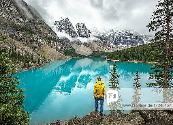 Young man looking at mountains  cloudy mountain peaks  reflection in turquoise glacial lake  Moraine Lake  Valley of the Ten Peaks  Rocky Mountains  Banff National Park  Alberta Province  Canada  North America