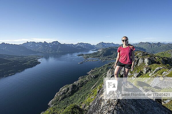 Junge Wanderin steht auf Felsen  Fjord Raftsund und Berge  Blick vom Gipfel des Dronningsvarden oder Stortinden  Vesterålen  Norwegen  Europa