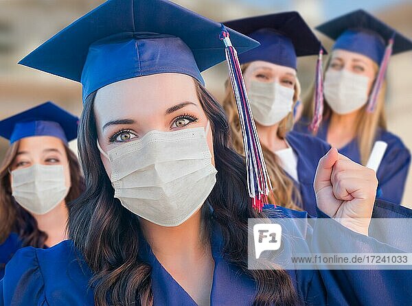 Several female graduates in cap and gown wearing medical face masks