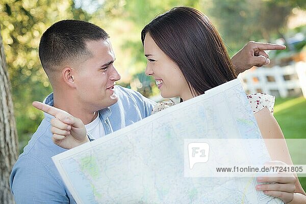 Lost and confused mixed-race couple looking over A map outside together