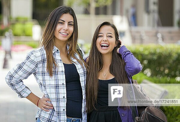 Portrait of two attractive mixed race female students carrying backpack on school campus