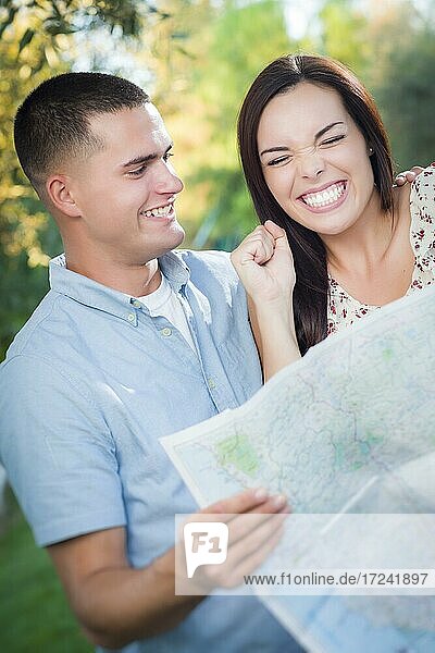 Happy mixed-race couple looking over A map outside together