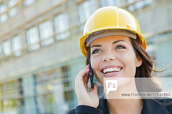 Junge Frau mit Helm auf Baustelle mit Handy,  Architektin,  Bauleiterin