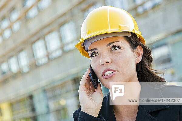 Junge Frau mit Helm auf Baustelle mit Handy,  Architektin,  Bauleiterin