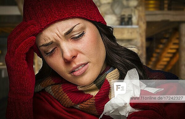 Warm angezogene kranke Frau in der Kabine mit Taschentuch