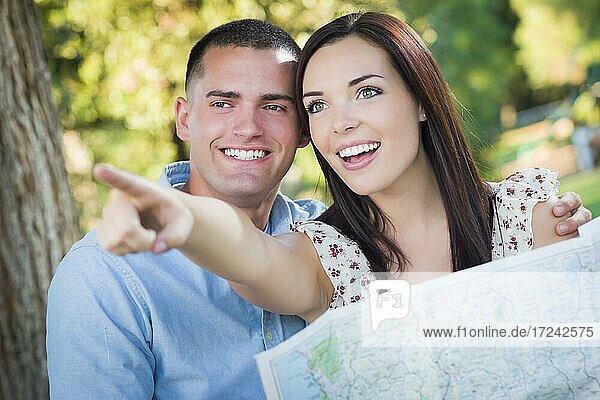 Glückliches gemischtrassiges Paar über eine Karte und die Seiten außerhalb zusammen suchen