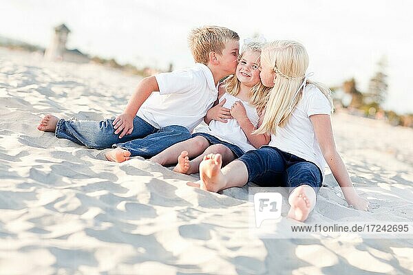 Adorable sibling children kissing the youngest girl at the beach