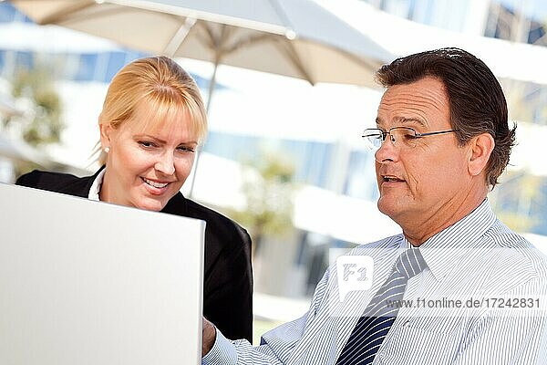 Handsome businessman working on the laptop with attractive female colleague outdoors