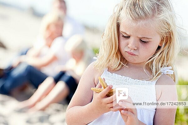 Adorable little blonde girl with starfish at the beach