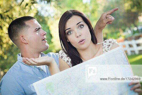 Lost and confused mixed-race couple looking over A map outside together