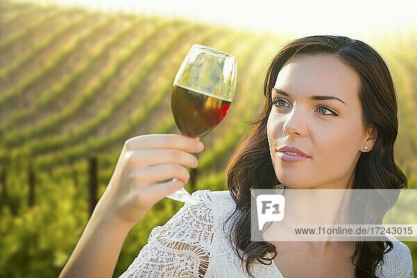 Hübsche gemischtrassige junge Frau genießt ein Glas Wein im Weinberg