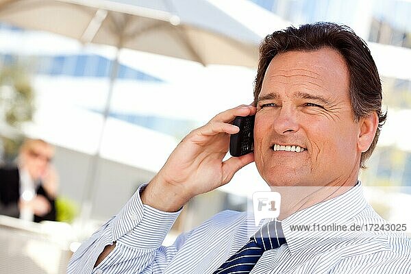 Confident  handsome businessman smiles as he talks on his cell phone