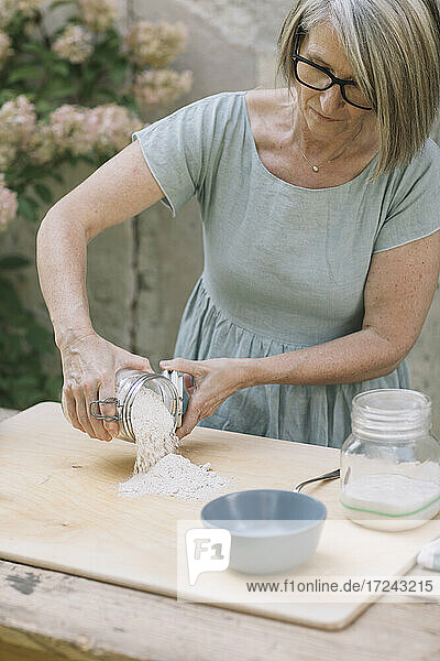 Ältere Frau  die Mehl auf ein Brett im Hinterhof legt