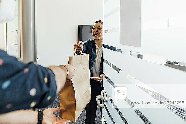Lächelnde Geschäftsfrau  die eine Essenslieferung im Büro entgegennimmt