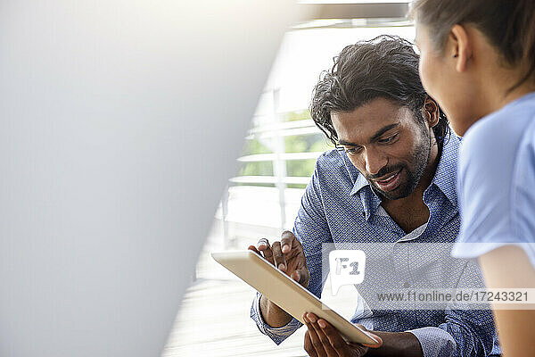 Businessman using digital tablet while discussing with female colleague at office