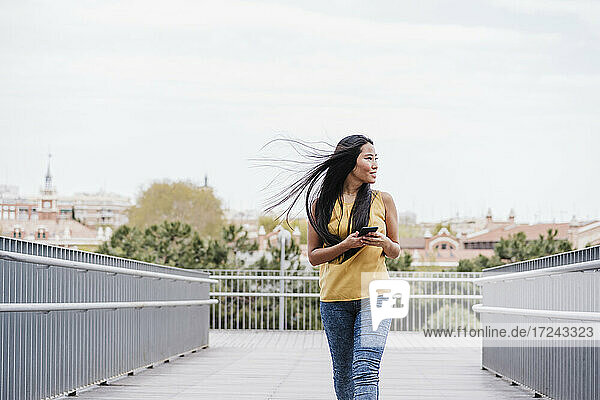 Beautiful woman with tousled hair looking away while walking on elevated walkway