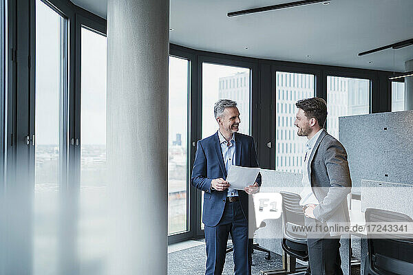 Smiling business people with document in meeting at office