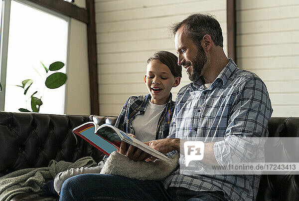 Vater und Sohn lesen ein Buch  während sie zu Hause sitzen