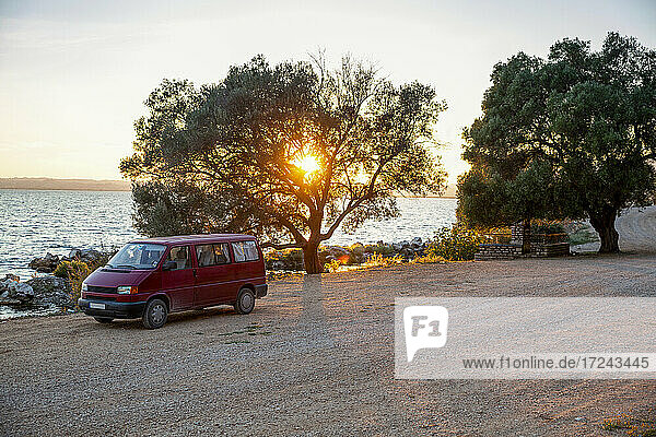 Sonnenuntergang über einem auf einer unbefestigten Straße geparkten Lieferwagen im Amvrakikos Wetlands National Park