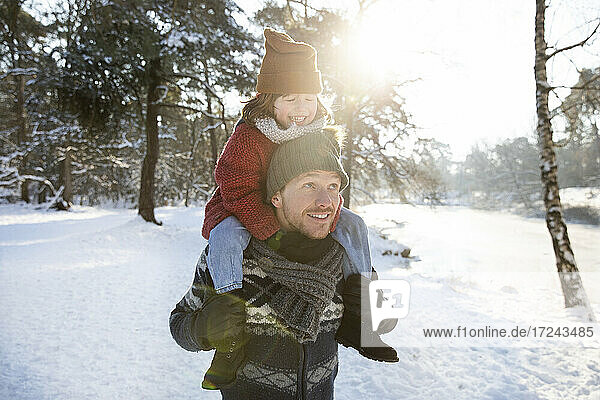 Vater trägt Sohn auf der Schulter im Winter an einem sonnigen Tag