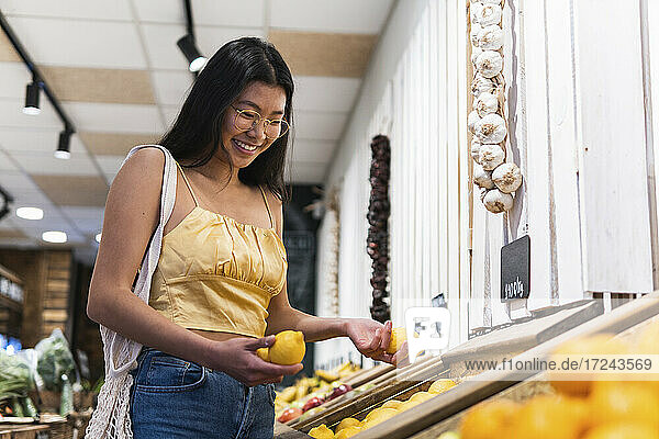 Lächelnde Frau beim Kauf von Zitronen im Lebensmittelgeschäft