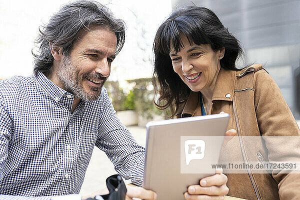 Älteres Unternehmerpaar arbeitet auf der Terrasse an einem digitalen Tablet