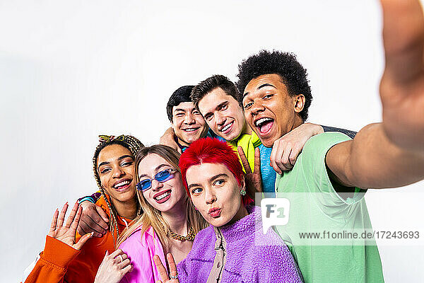 Happy young man taking selfie with male and female friends on white background