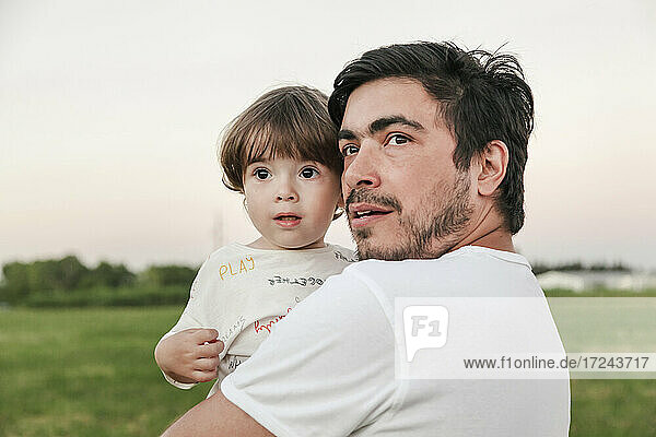 Father carrying son while looking away