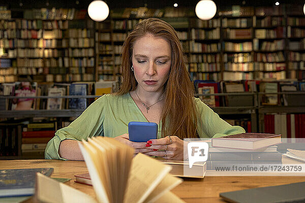 Schöne Frau benutzt Mobiltelefon in Bibliothek