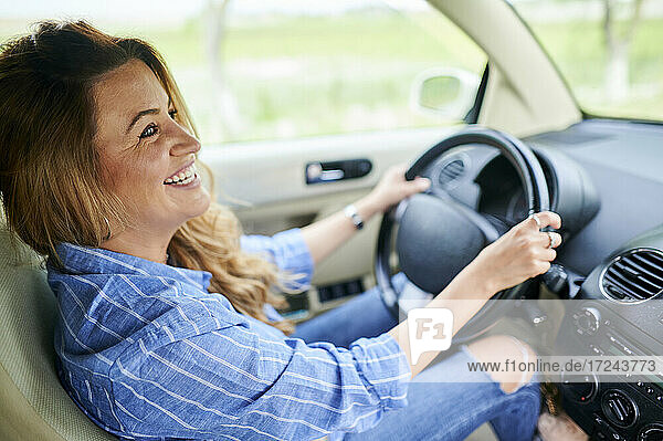 Happy woman looking away while driving car