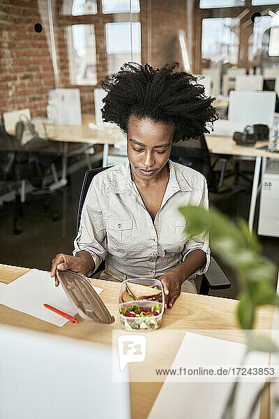 Afro-Geschäftsfrau beim Öffnen eines Containers in der Mittagspause im Büro