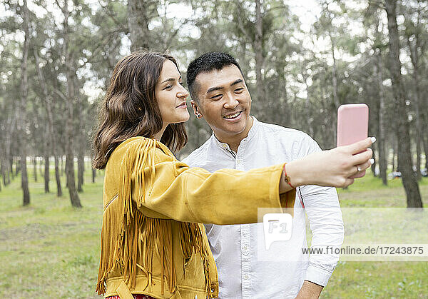 Man with beautiful woman taking selfie on smart phone at forest