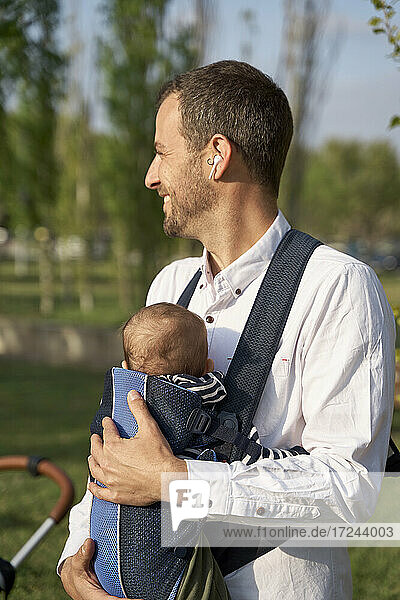 Mid adult man with son in baby carrier on sunny day