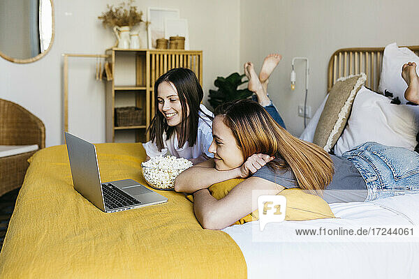 Junge Frau mit Freundin schaut Film im Schlafzimmer