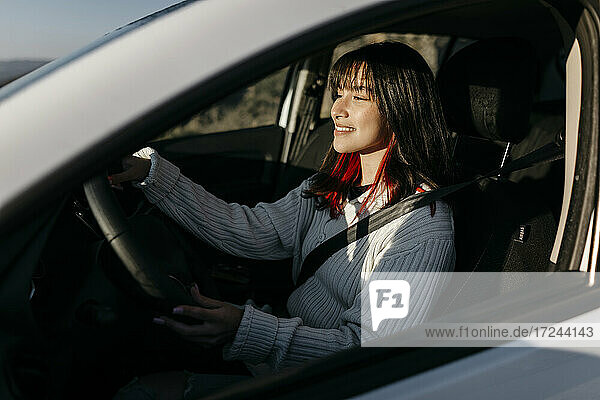 Smiling woman driving car during road trip