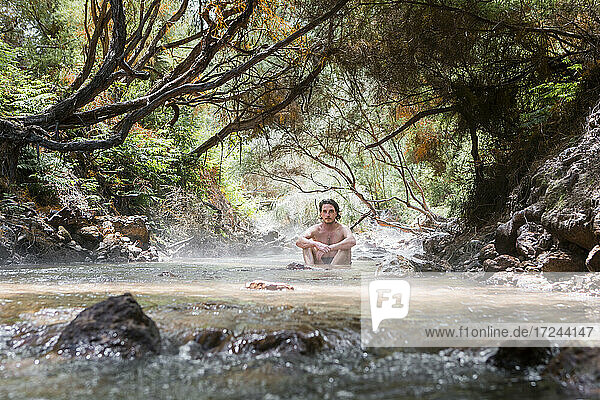 Mann ohne Hemd entspannt sich im Thermalfluss  Rotorura  Neuseeland