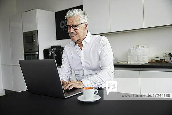 Ältere Berufstätige arbeiten am Laptop in der Cafeteria