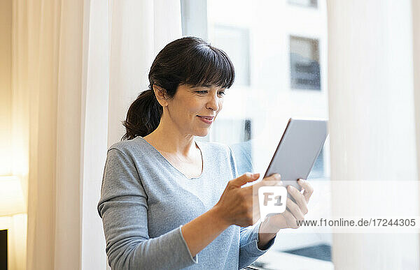 Lächelnde Frau mit digitalem Tablet in einer Hotelsuite