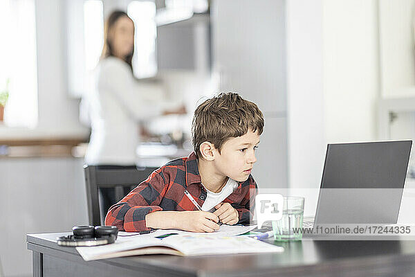Junge  der sich beim Lernen auf seinen Laptop zu Hause konzentriert