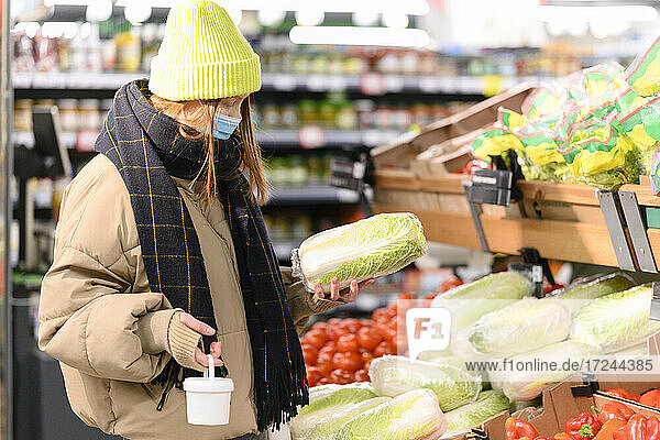 Junge Frau kauft Gemüse im Supermarkt während COVID-19