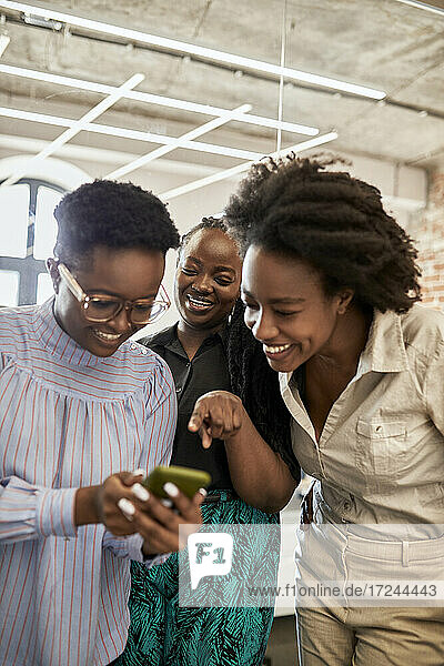 Weibliche Fachkräfte diskutieren über Smartphone im Coworking-Büro