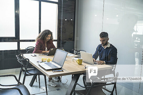 Männliche und weibliche Fachkräfte arbeiten an einem Laptop in einem Coworking-Büro
